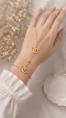 قطعة عصرية وراقية تتكوّن من سلسلة ذهبية رفيعة تربط المعصم بخاتم الإصبع    CHANNEL    Bracelet de Main Chaîne Élégance Dorée